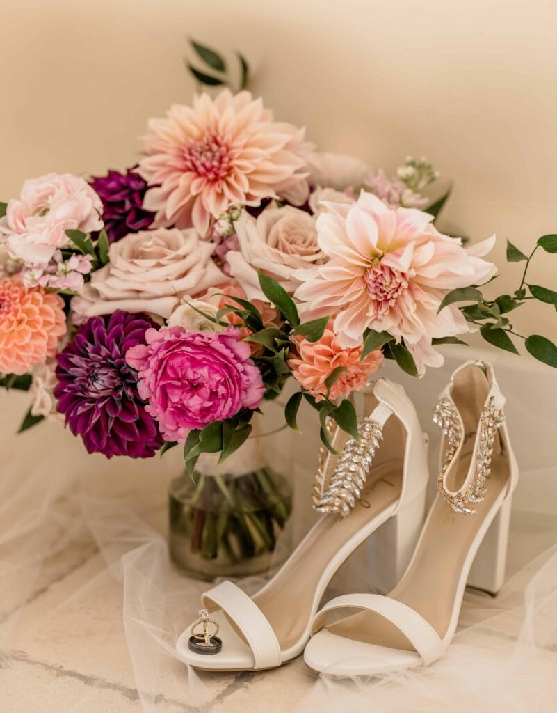 Boho wedding attire details of a brides bouquet, rings, and heels.