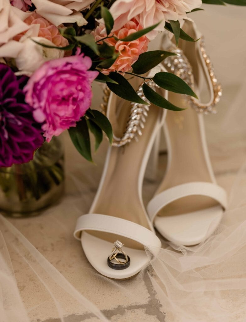 Boho wedding attire details of a brides bouquet, rings, and heels.