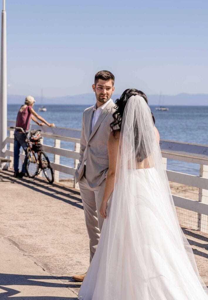 Groom smiling at bride during their first look. Santa Cruz pier beach wedding.