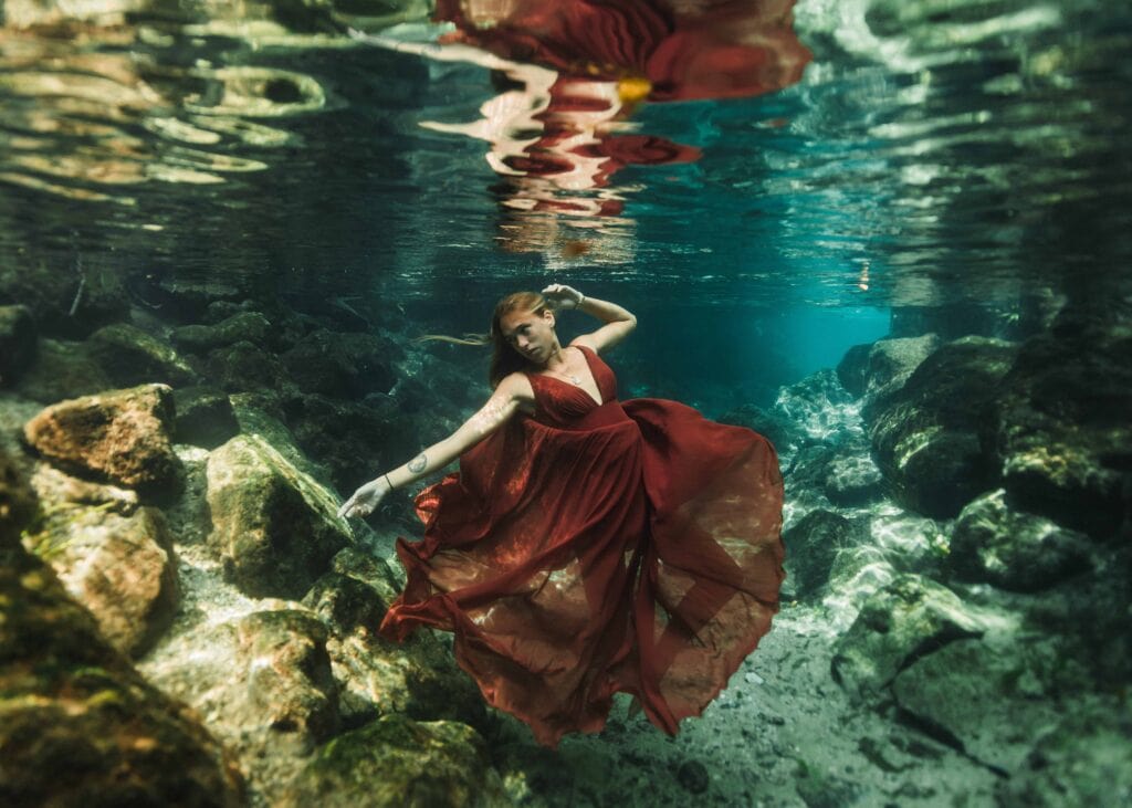 girl wearing red flowy dress underwater