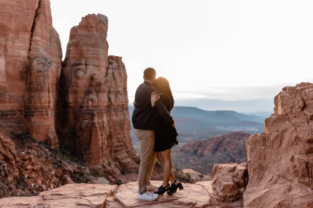 Couple wearing all black looking into the sunset at the top of Cathedral Rock in Sedona Arizona