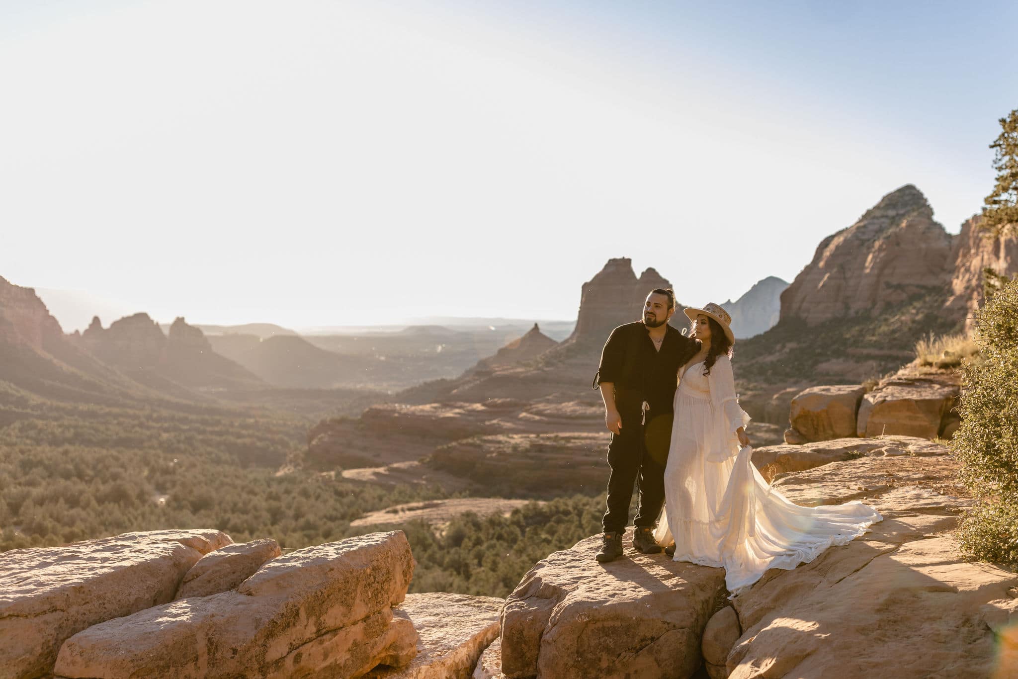 couple stands on edge of rock at boho elopement