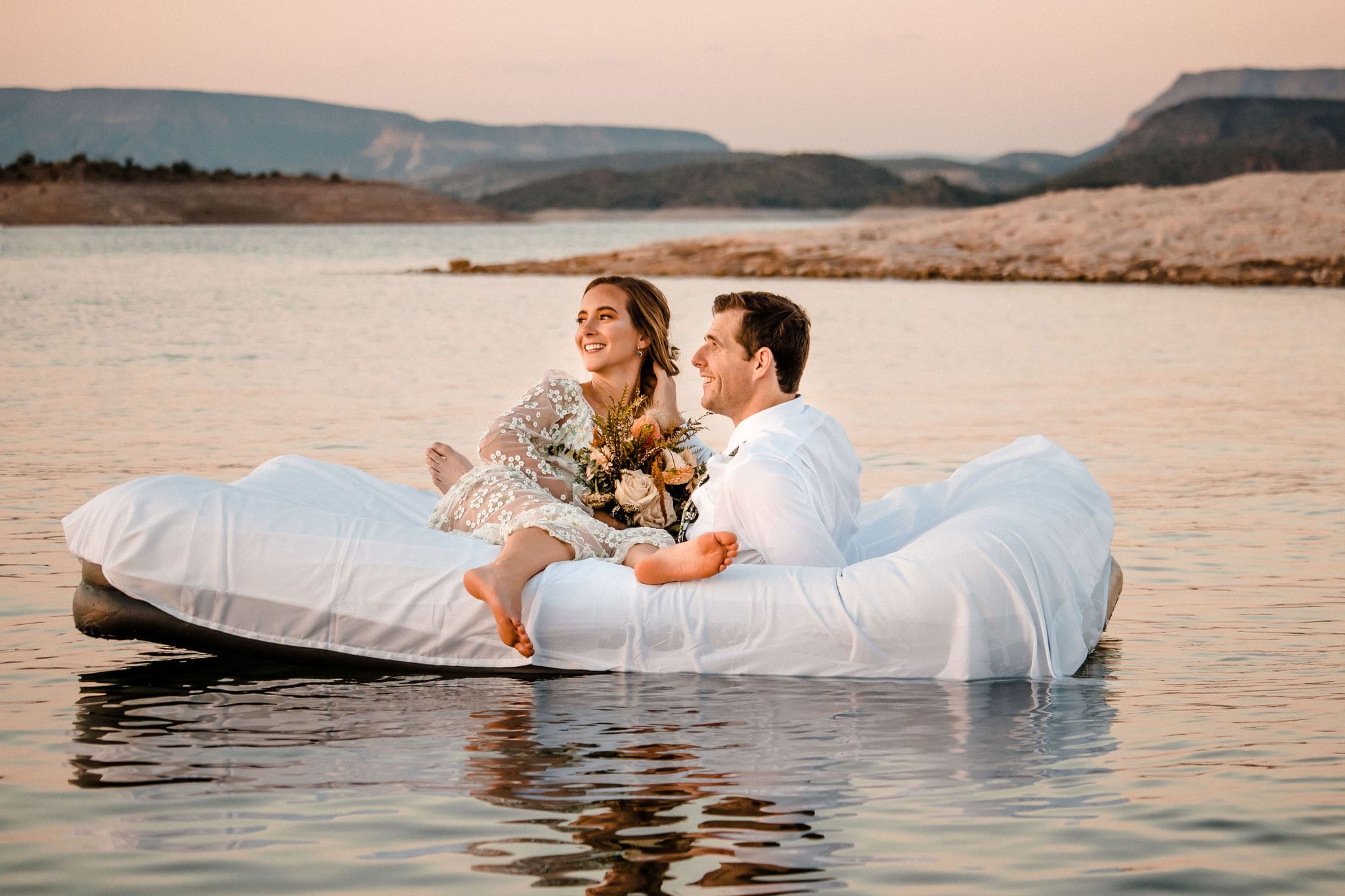 couple floats on air mattress as lakeside elopement ideas
