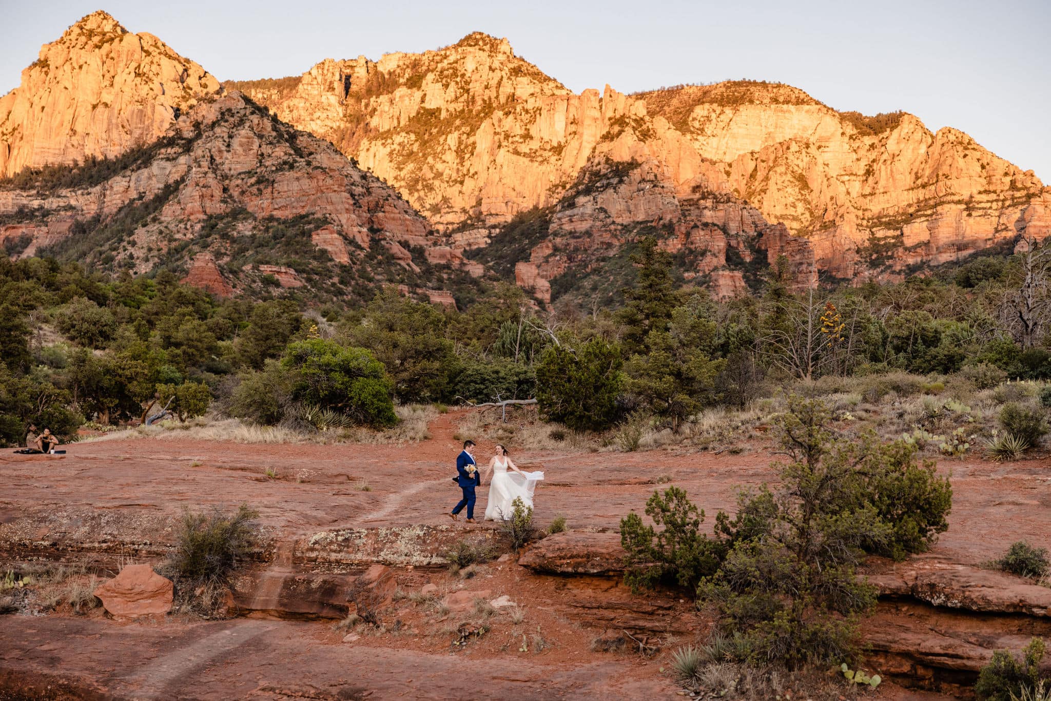 couple walks along sunset Arizona rocks at elopement location