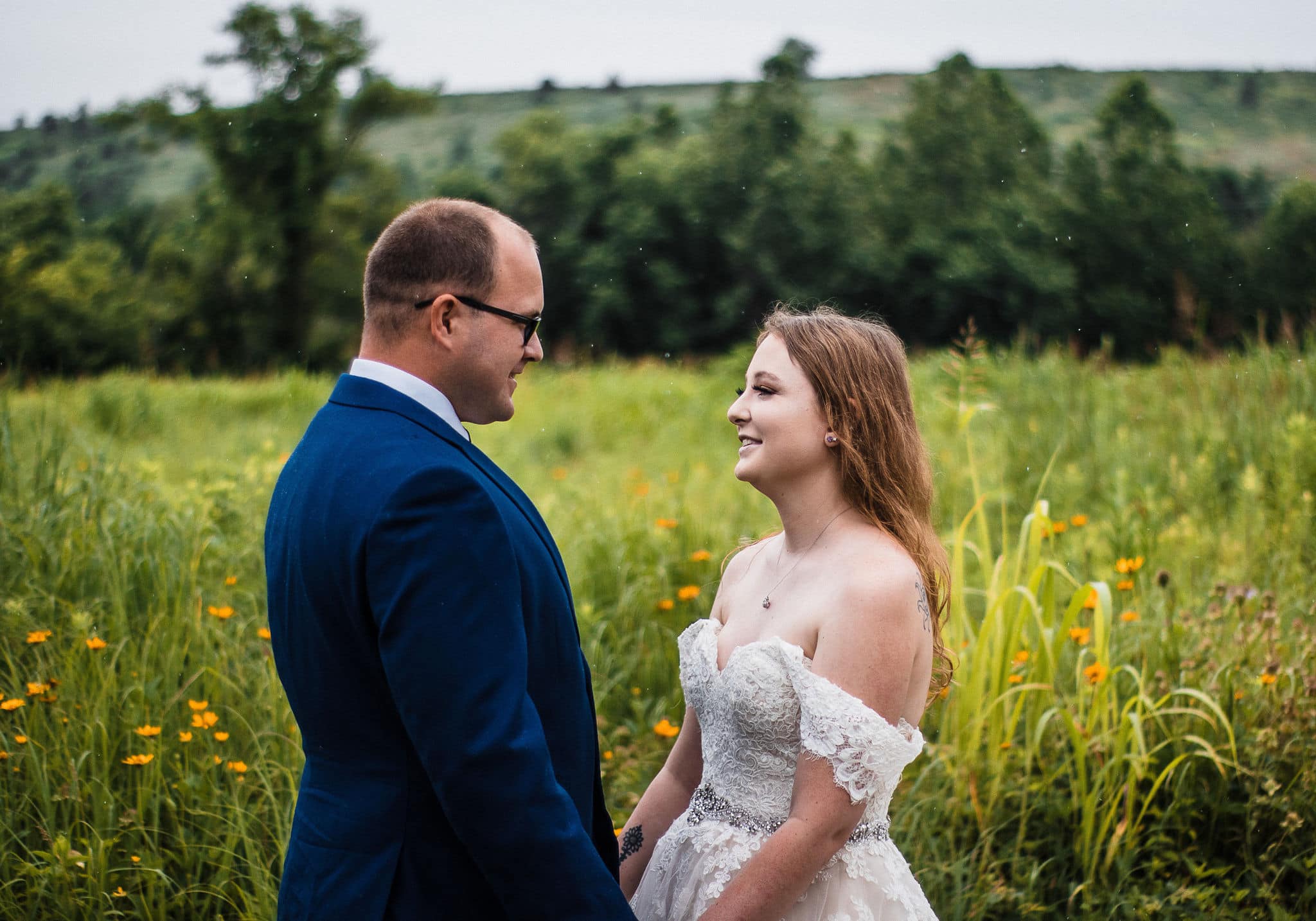 couple holds hands in green wildflower fields