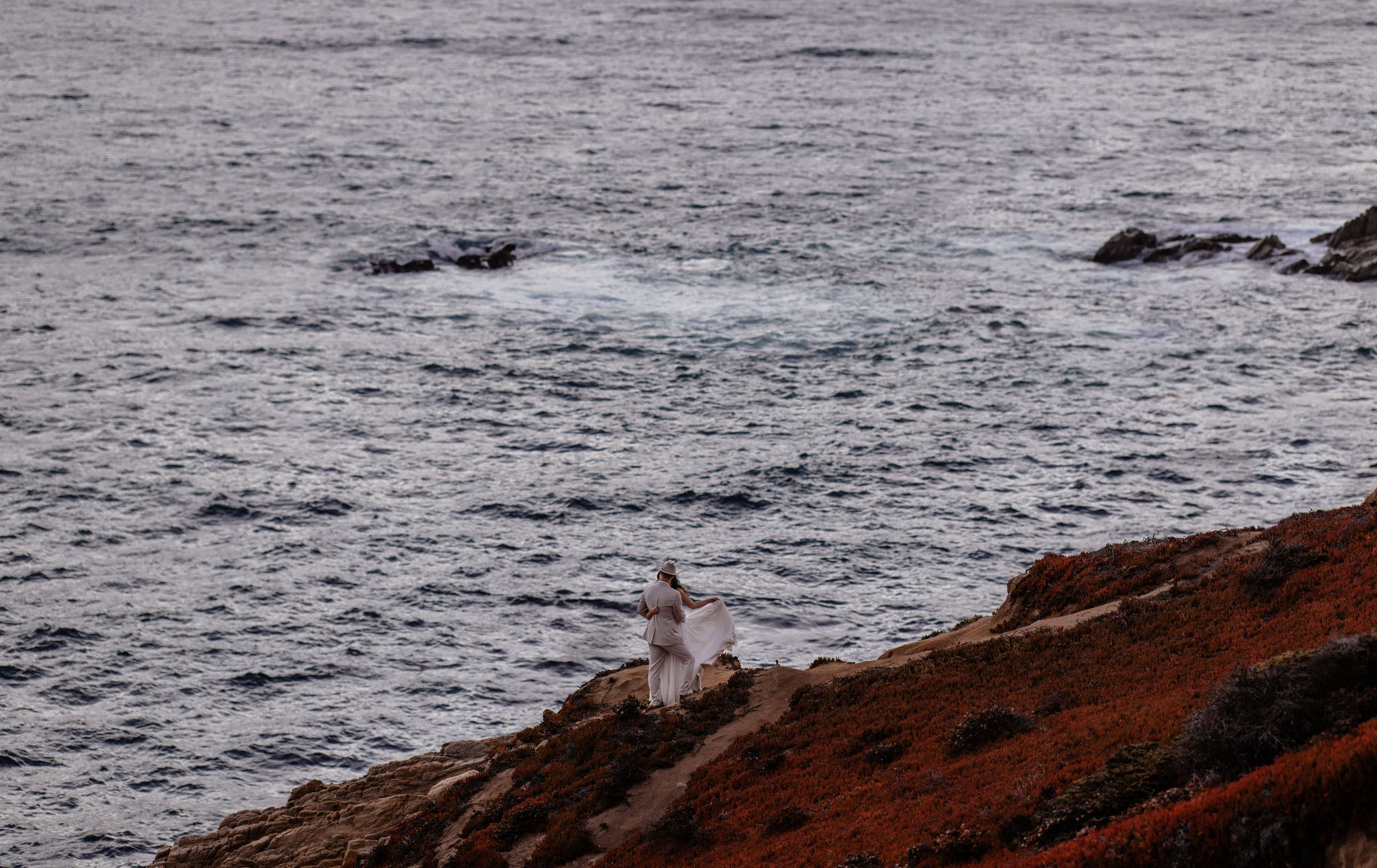 couple stands along rocks at Big Sur California elopement location