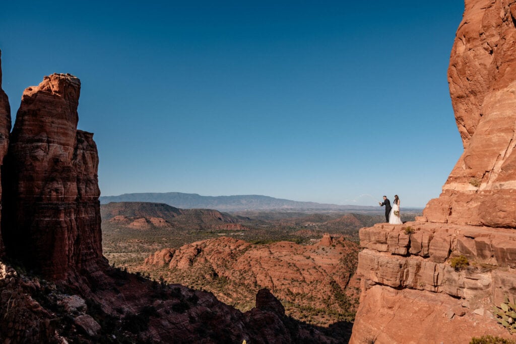 couple stands on cliff edge at Sedona elopement